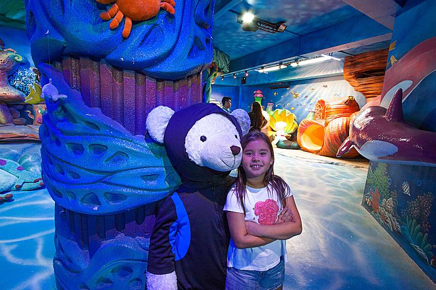 A smiling kid poses with a cartoon bear at Teddy Bear Museum Pattaya