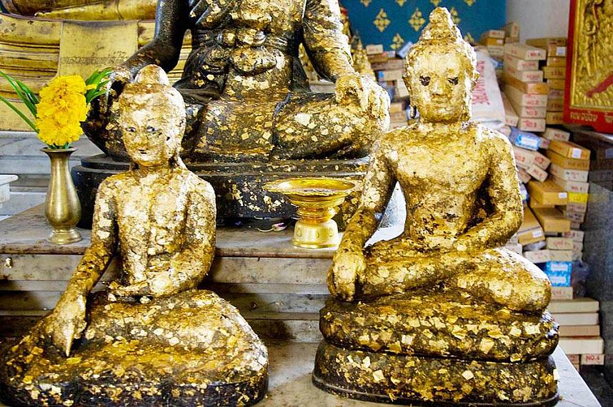 Worshipers put gold leaves on the Buddha statues at Wat Chai Mongkol
