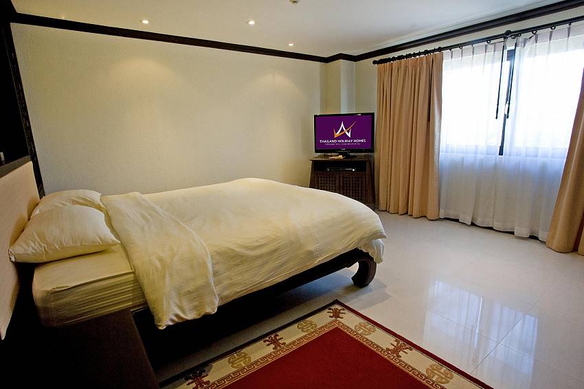 Master bedroom with king-size bed and TV at Nirvana Place Pattaya